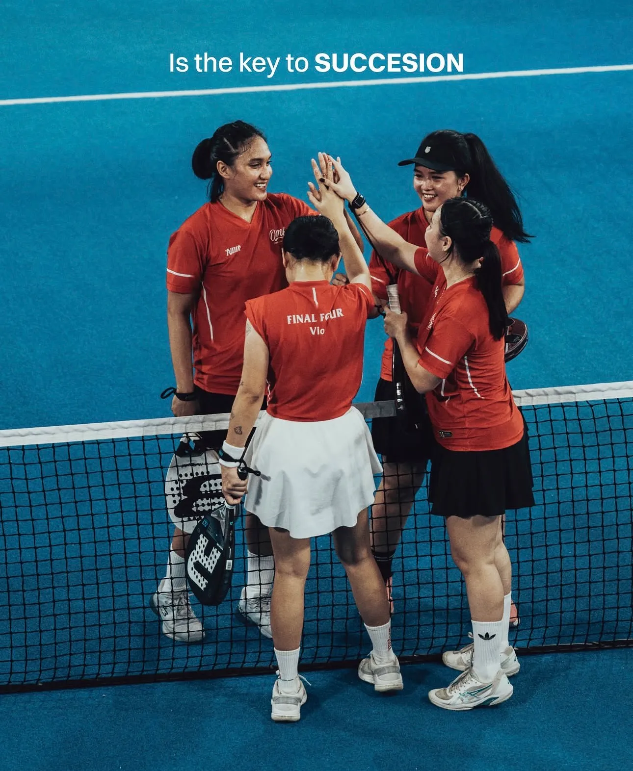 Empat pemain padel berjersey NOIR merah saling tos di samping net.