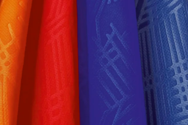 Gulungan kain Emboss berwarna oranye, merah, dan biru dengan motif timbul