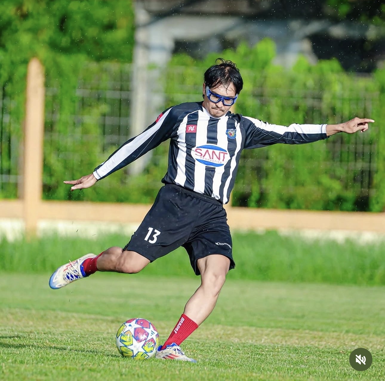Pemain Perngabong menendang bola dengan kit kandang belang hitam-putih